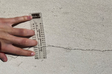 Personne mesurant une fissure avec un mètre ruban. Raval Façades 64.