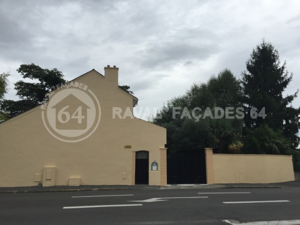 Façade de bâtiment beige avec porte et arbres